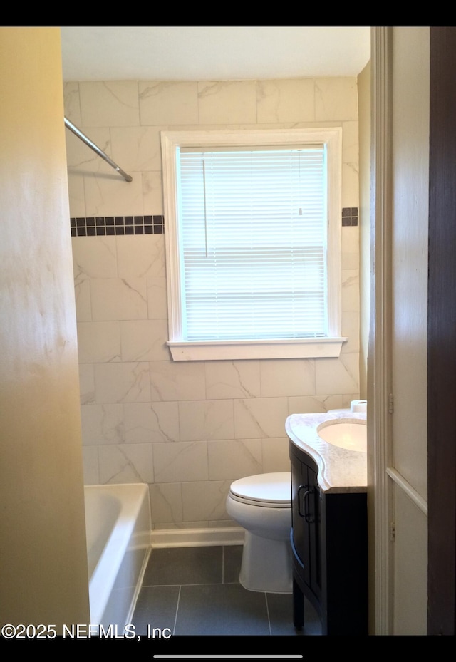 full bathroom with vanity, tiled shower / bath, tile patterned flooring, toilet, and tile walls