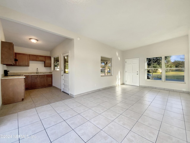 unfurnished living room with sink, light tile patterned floors, and lofted ceiling