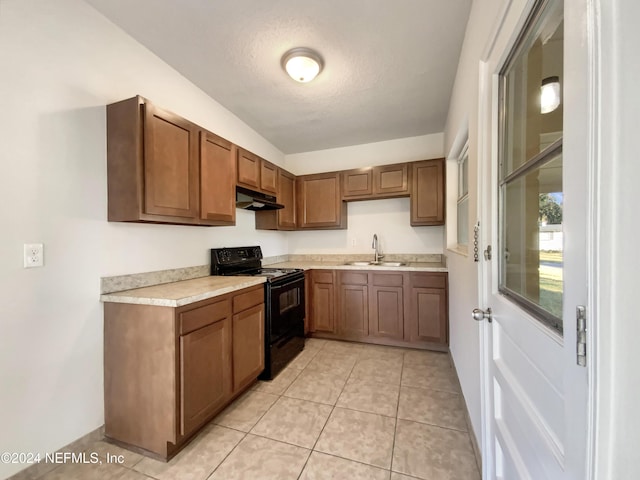 kitchen featuring a textured ceiling, light tile patterned floors, sink, and black / electric stove