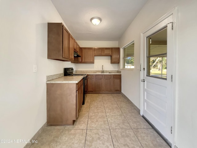 kitchen featuring black range with electric stovetop, sink, light tile patterned floors, and a textured ceiling