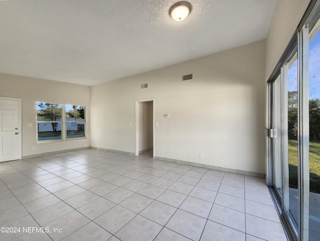 unfurnished room with a textured ceiling and light tile patterned flooring