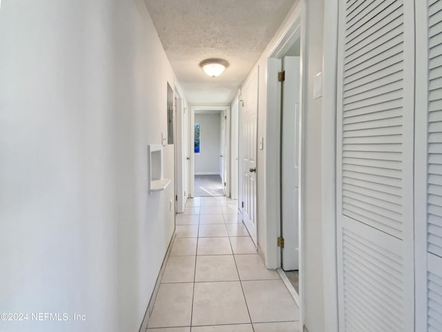 corridor with light tile patterned floors and a textured ceiling