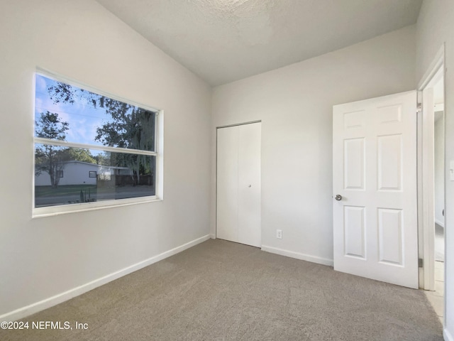 unfurnished bedroom featuring carpet, a textured ceiling, and a closet