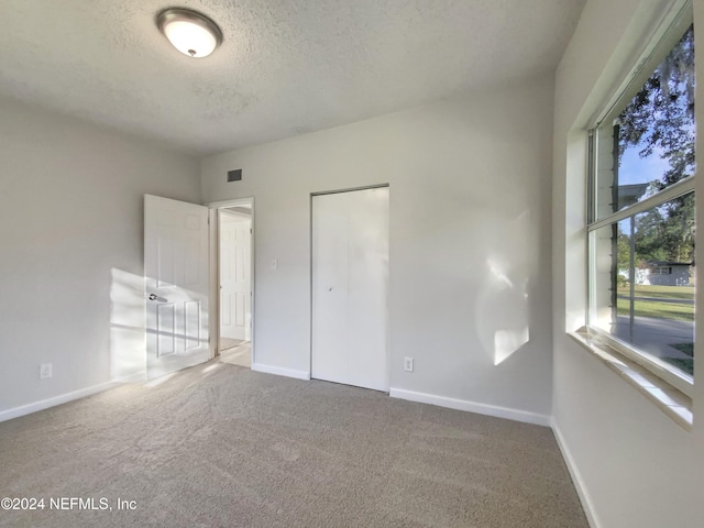 unfurnished bedroom featuring a textured ceiling, carpet floors, and a closet