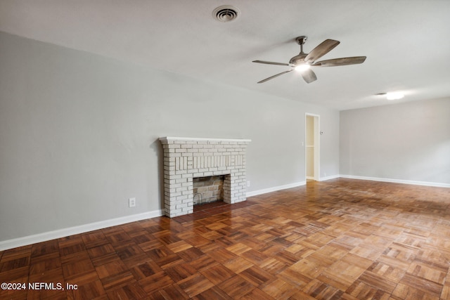 unfurnished living room with dark parquet floors, a brick fireplace, and ceiling fan