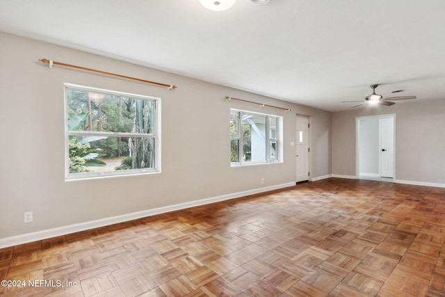 empty room with ceiling fan, a healthy amount of sunlight, and light parquet floors