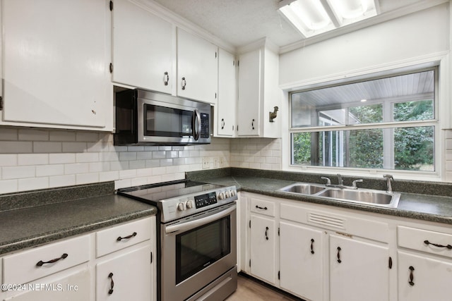 kitchen with white cabinets, appliances with stainless steel finishes, crown molding, and sink