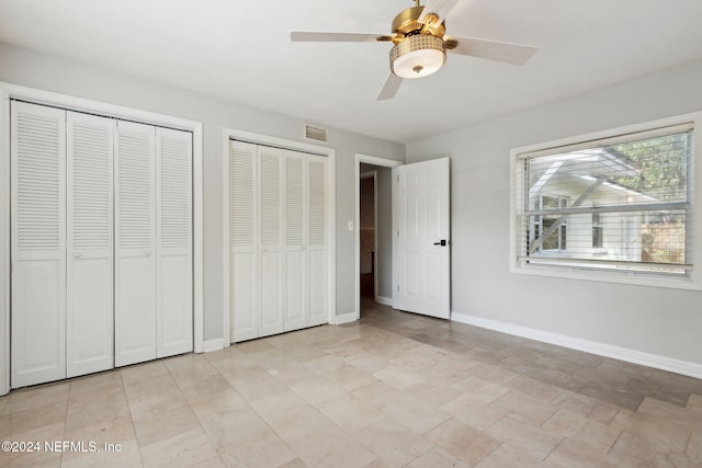 unfurnished bedroom with ceiling fan and multiple closets