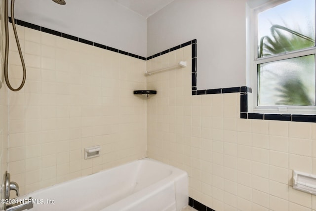 bathroom featuring tiled shower / bath combo and tile walls