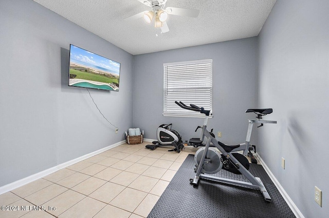 exercise area featuring ceiling fan, light tile patterned flooring, and a textured ceiling