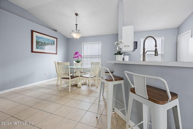 dining area featuring a textured ceiling, vaulted ceiling, plenty of natural light, and light tile patterned flooring