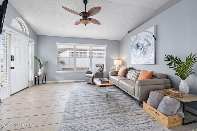 living room with ceiling fan, lofted ceiling, a textured ceiling, and light tile patterned floors