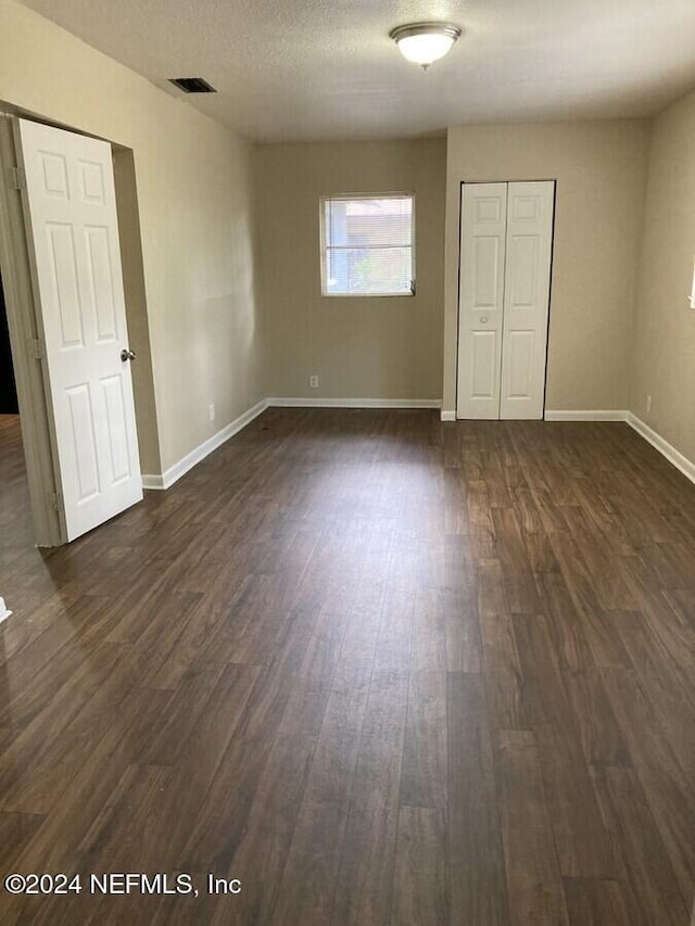 unfurnished bedroom with a textured ceiling and dark hardwood / wood-style floors