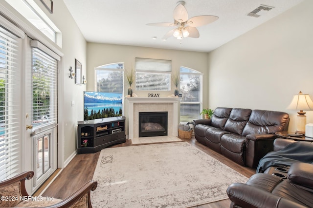 living room with a tile fireplace, hardwood / wood-style flooring, and ceiling fan