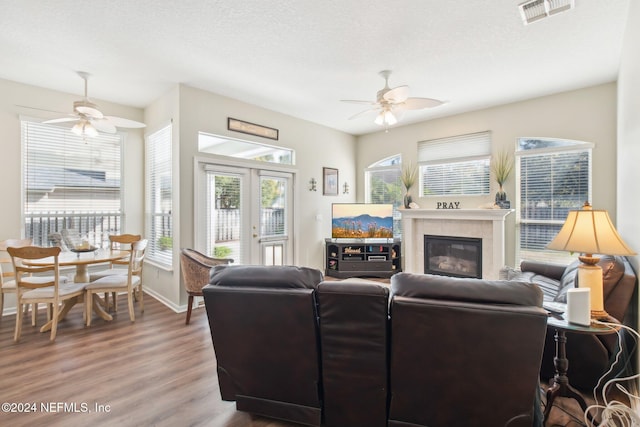 living room featuring a tile fireplace, a textured ceiling, hardwood / wood-style flooring, and ceiling fan