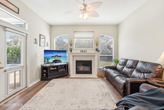 living room featuring a tile fireplace, wood-type flooring, and ceiling fan