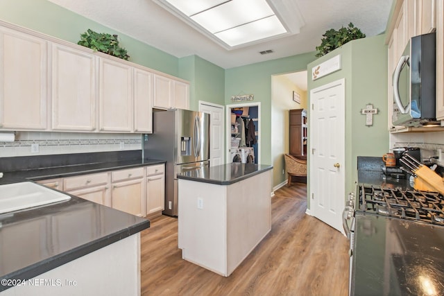 kitchen featuring white cabinets, washing machine and dryer, appliances with stainless steel finishes, and light hardwood / wood-style flooring