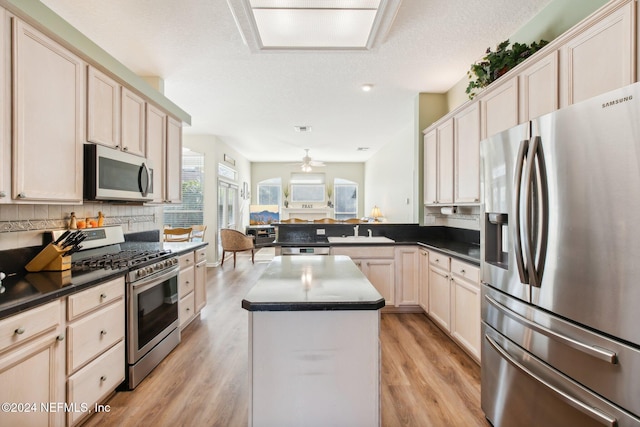 kitchen featuring a textured ceiling, light hardwood / wood-style floors, sink, and stainless steel appliances