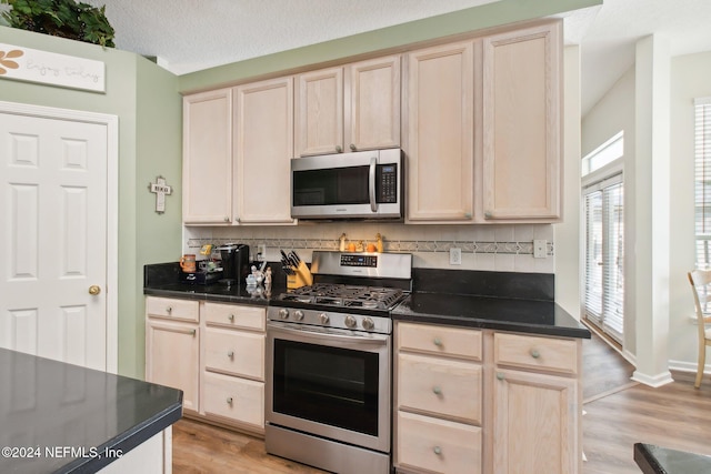 kitchen with tasteful backsplash, light hardwood / wood-style flooring, a textured ceiling, and appliances with stainless steel finishes