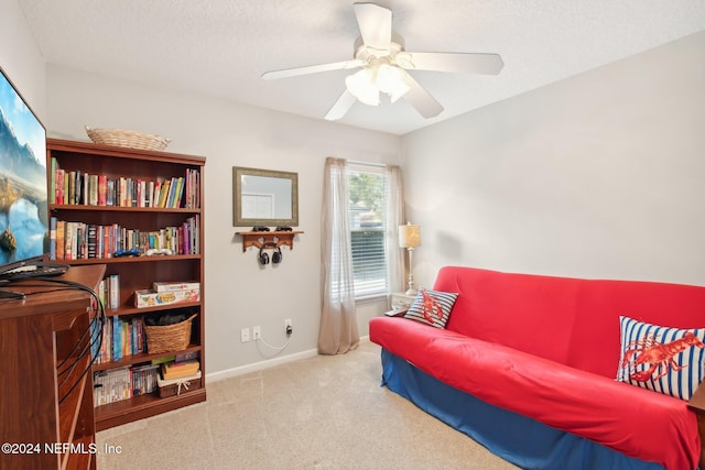 living area featuring a textured ceiling, carpet floors, and ceiling fan