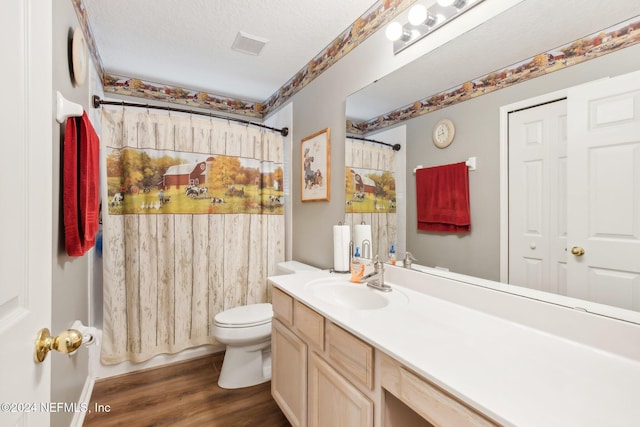 bathroom featuring hardwood / wood-style flooring, vanity, toilet, and a textured ceiling