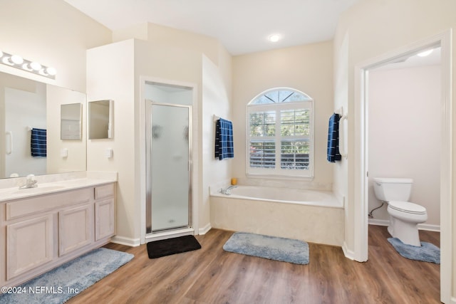 full bathroom with plus walk in shower, hardwood / wood-style floors, vanity, and toilet