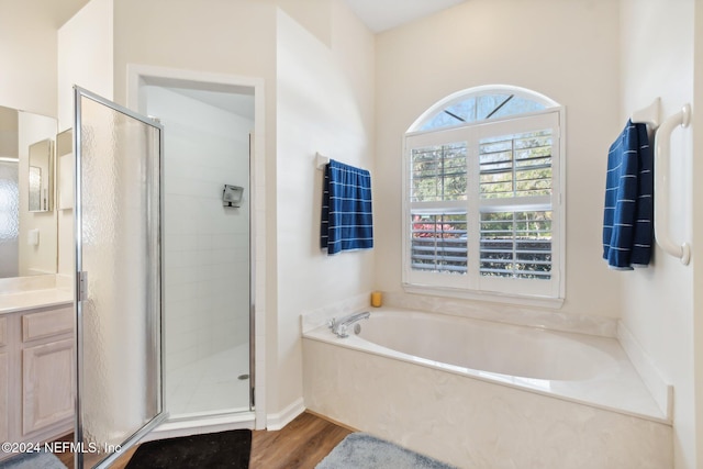 bathroom featuring plus walk in shower, vanity, and hardwood / wood-style flooring