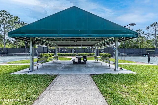 view of home's community featuring tennis court, a yard, and a patio