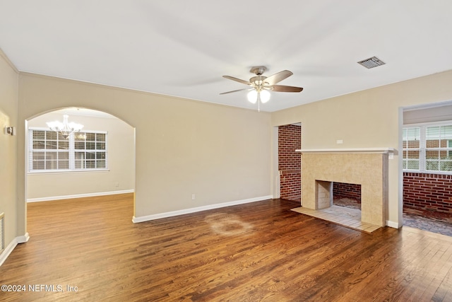 unfurnished living room with a tile fireplace, ceiling fan with notable chandelier, and hardwood / wood-style flooring