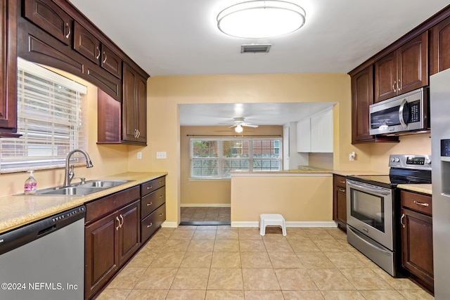 kitchen with sink, ceiling fan, light tile patterned floors, appliances with stainless steel finishes, and dark brown cabinets