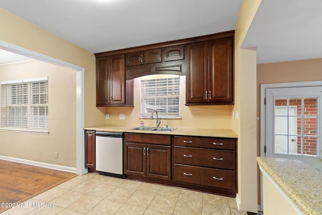 kitchen with dark brown cabinetry, sink, light tile patterned flooring, and stainless steel dishwasher