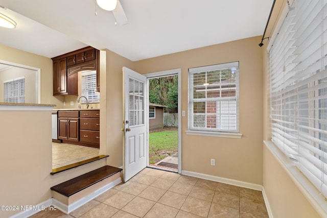 doorway featuring ceiling fan, sink, and light tile patterned flooring