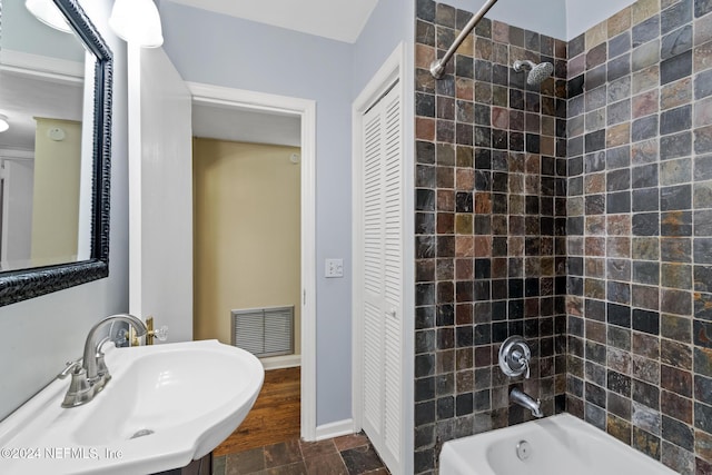 bathroom featuring tiled shower / bath combo and sink