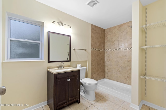 bathroom with toilet, vanity, tiled shower, and tile patterned floors