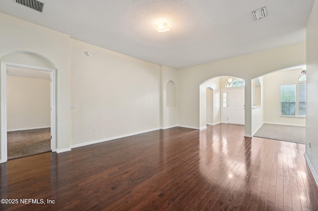 unfurnished room with a textured ceiling and dark wood-type flooring