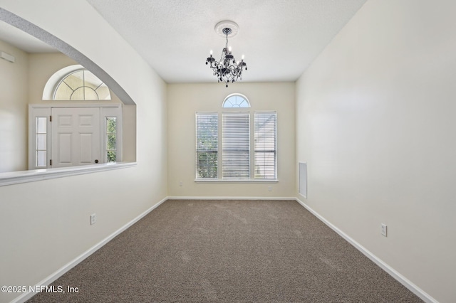 spare room with carpet floors and an inviting chandelier