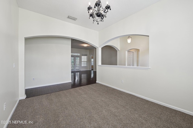 empty room featuring a chandelier and dark colored carpet