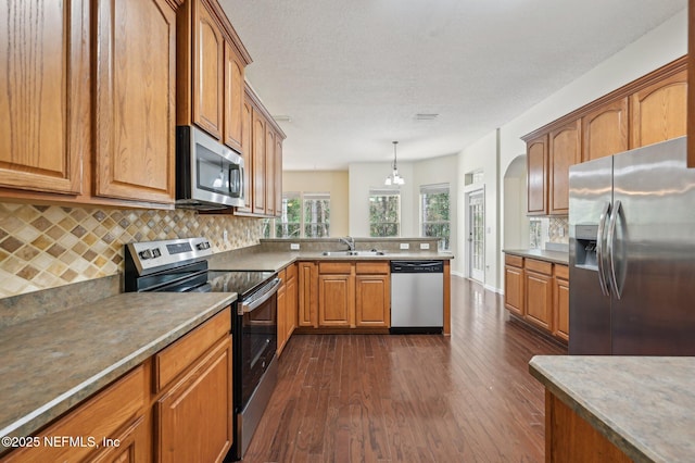 kitchen featuring backsplash, sink, decorative light fixtures, and appliances with stainless steel finishes