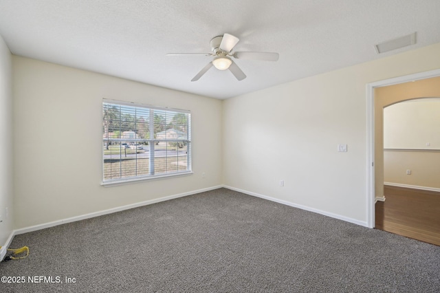 spare room with dark colored carpet and ceiling fan