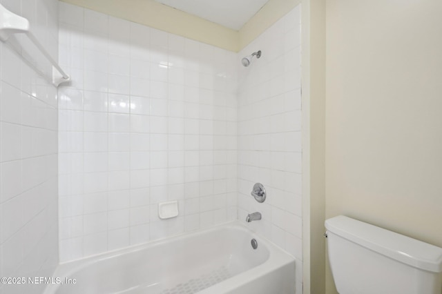 bathroom with toilet and tiled shower / bath