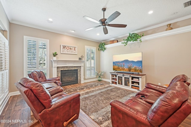 living room featuring a fireplace, hardwood / wood-style floors, a textured ceiling, and crown molding