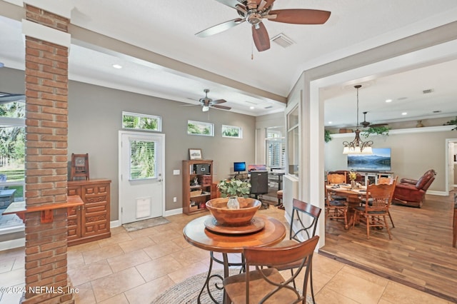 dining area featuring light tile patterned floors, ceiling fan with notable chandelier, decorative columns, and ornamental molding