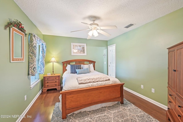 bedroom featuring ceiling fan, dark hardwood / wood-style flooring, and a textured ceiling