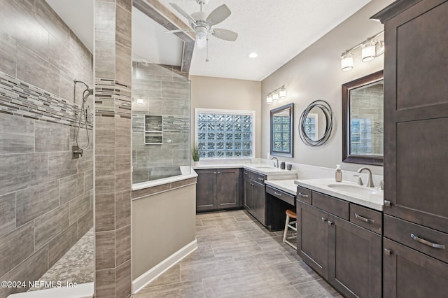 bathroom featuring a textured ceiling, vanity, ceiling fan, and tiled shower