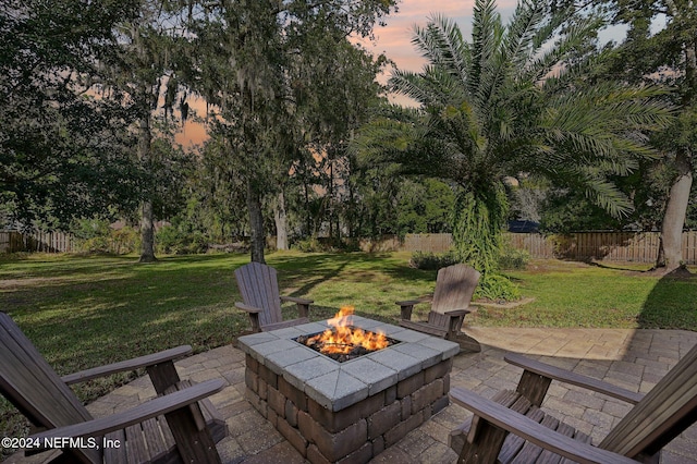 patio terrace at dusk featuring a lawn and an outdoor fire pit