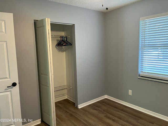 unfurnished bedroom with a closet, dark wood-type flooring, and a textured ceiling