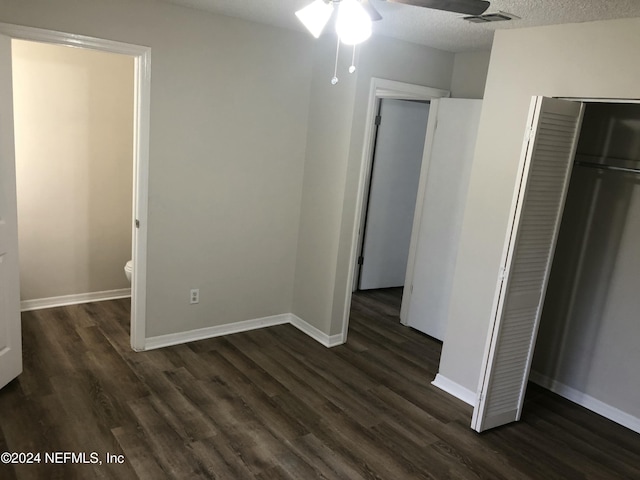 unfurnished bedroom featuring a textured ceiling, dark hardwood / wood-style flooring, and a closet