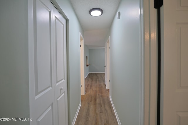 hallway with wood-type flooring and a textured ceiling