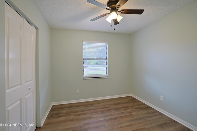 unfurnished bedroom with ceiling fan, dark hardwood / wood-style flooring, a textured ceiling, and a closet