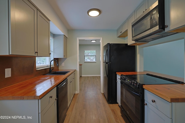 kitchen with sink, a wealth of natural light, butcher block counters, and black appliances